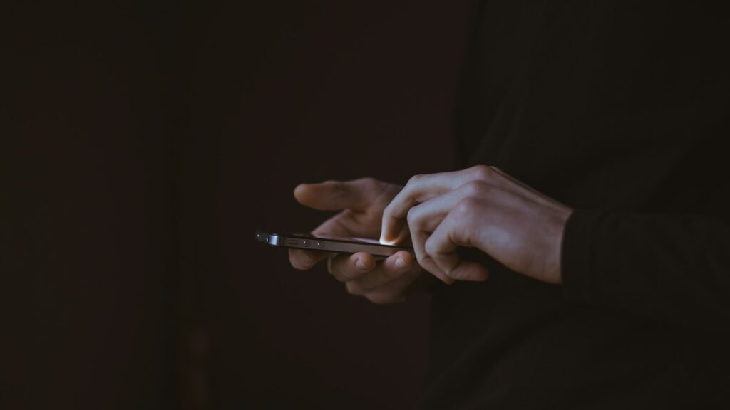 Mano sobre un móvil a punto de borrar mensajes de WhatsApp