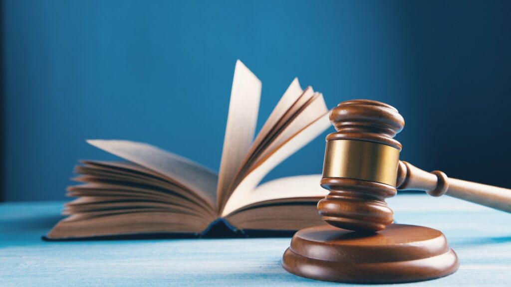 Código legal y portátil sobre la mesa, imagen de la prueba electrónica en la LEC